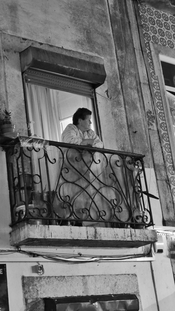 A woman surveils the Bairro Alto on a warm December night from her balcony. I love spying on people who are spying on people. 