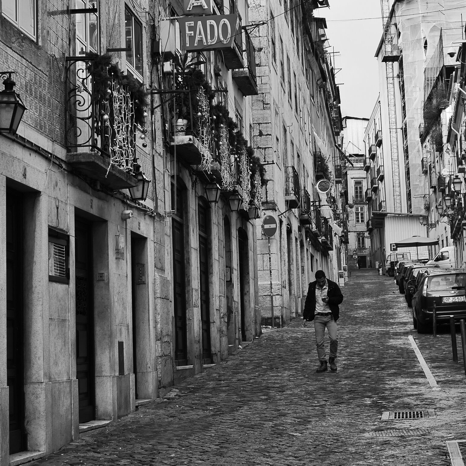 Man strolls in the Bairo Alto of Lisbon, the fado singing district packed with great restaurants featuring traditional dishes.
