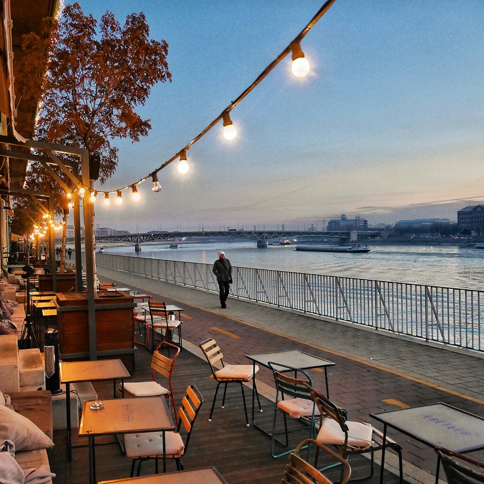 A lone stroller passes a riverside cafe at sunset on the Danube River in December.